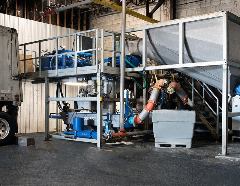 Industrial equipment is shown in a processing facility, featuring pumps and storage for liquid materials, demonstrating operational setup and workflow.