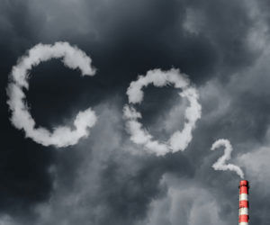 "Clouds forming the chemical symbol for carbon dioxide (CO₂) above a smokestack, highlighting pollution and environmental concerns."