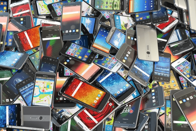A chaotic assortment of smartphones stacked together, showcasing various screens and designs. Illustrates the prevalence of mobile technology.
