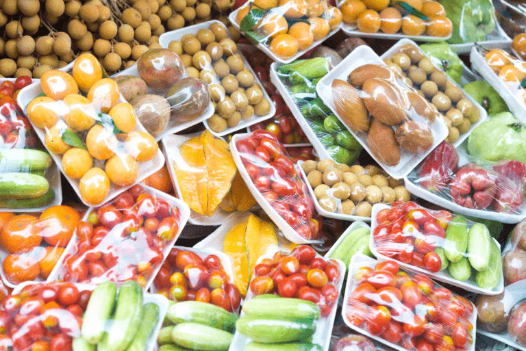 Colorful assortment of packaged fruits and vegetables arranged neatly in a market. Emphasizes fresh produce availability and variety.