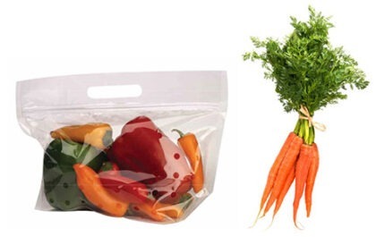 Colorful bell peppers in a clear bag alongside fresh, tied carrots. Ideal for showcasing healthy cooking ingredients.